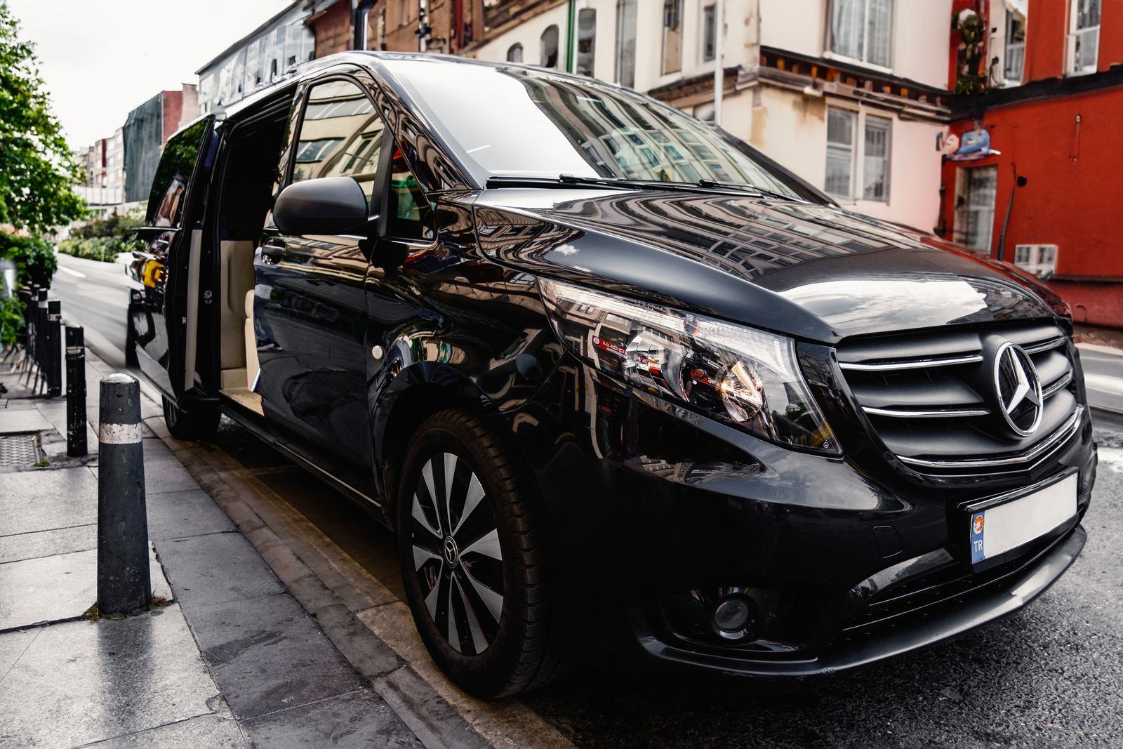 Black Mercedes passenger van parked on a city street with its door open